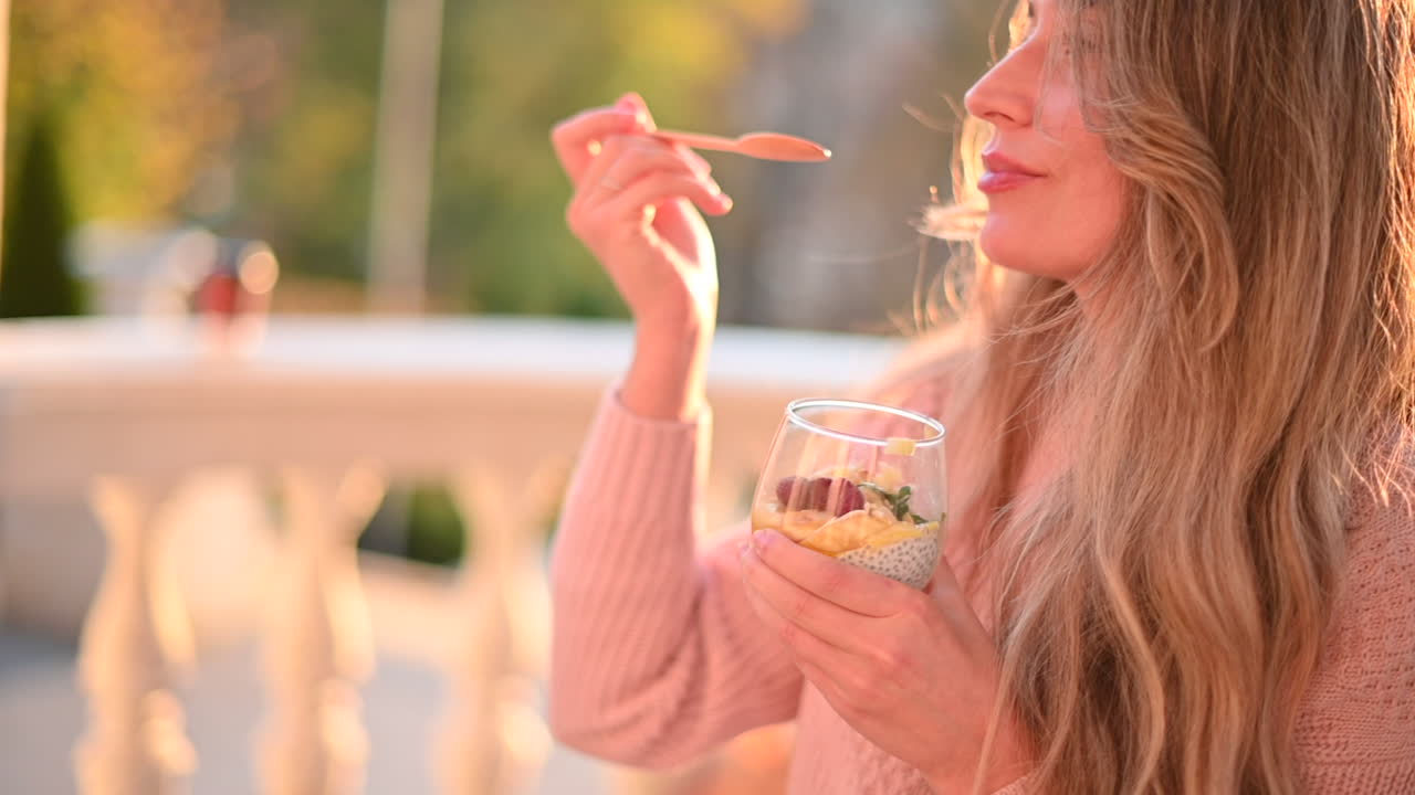 Woman eating a fruit salad with chia seeds in a park at the sunset