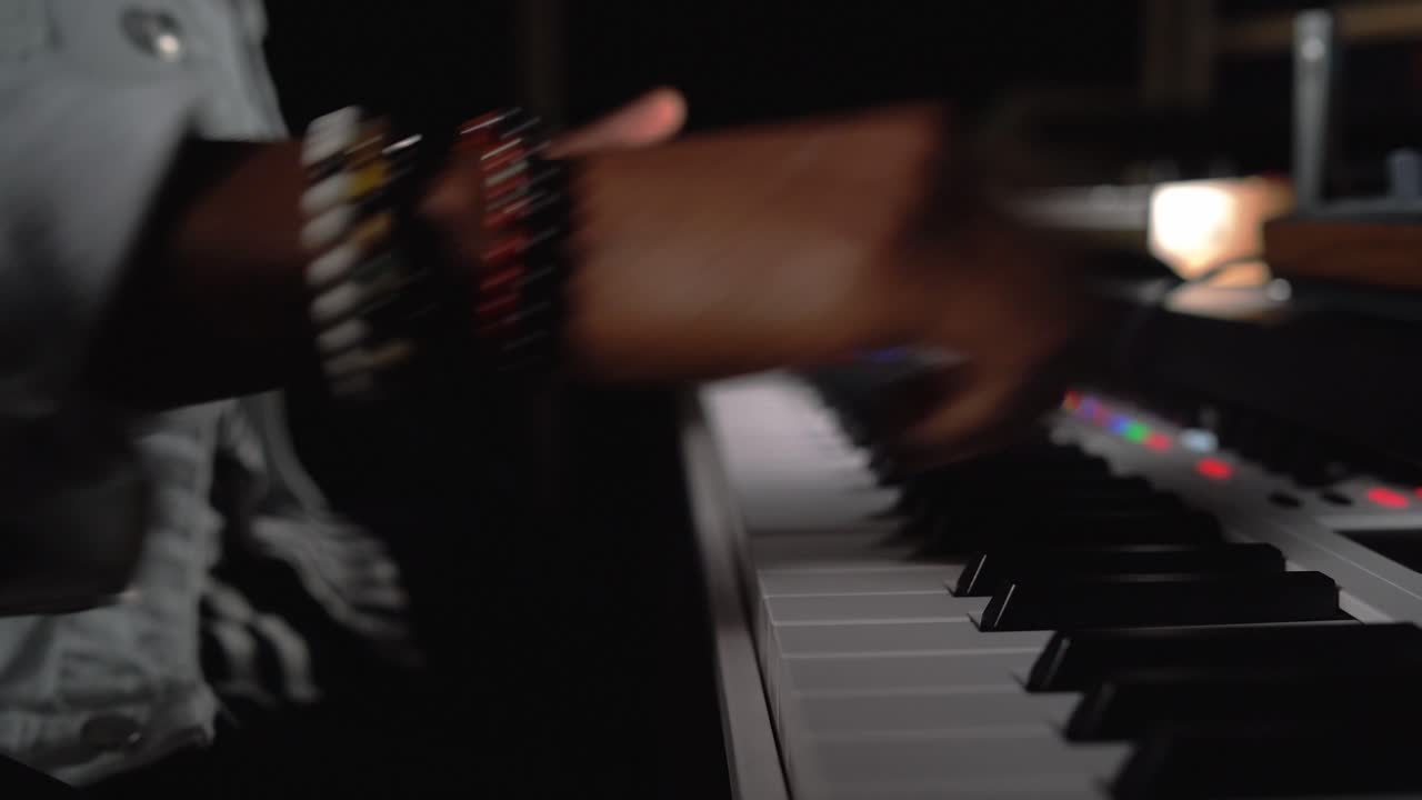 hombre negro anónimo tocando sintetizador en el estudio