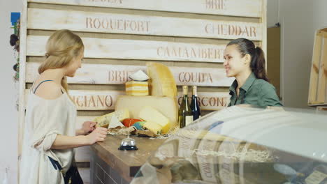 friendly salesclerk cheese advises the buyer it should be behind the counter about the larger cheese