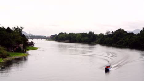 Lancha-Turística-Conduciendo-Por-El-Río-Kwai-Con-Pasajeros-Que-Llevan-Chalecos-Salvavidas-De-Color-Naranja-Brillante