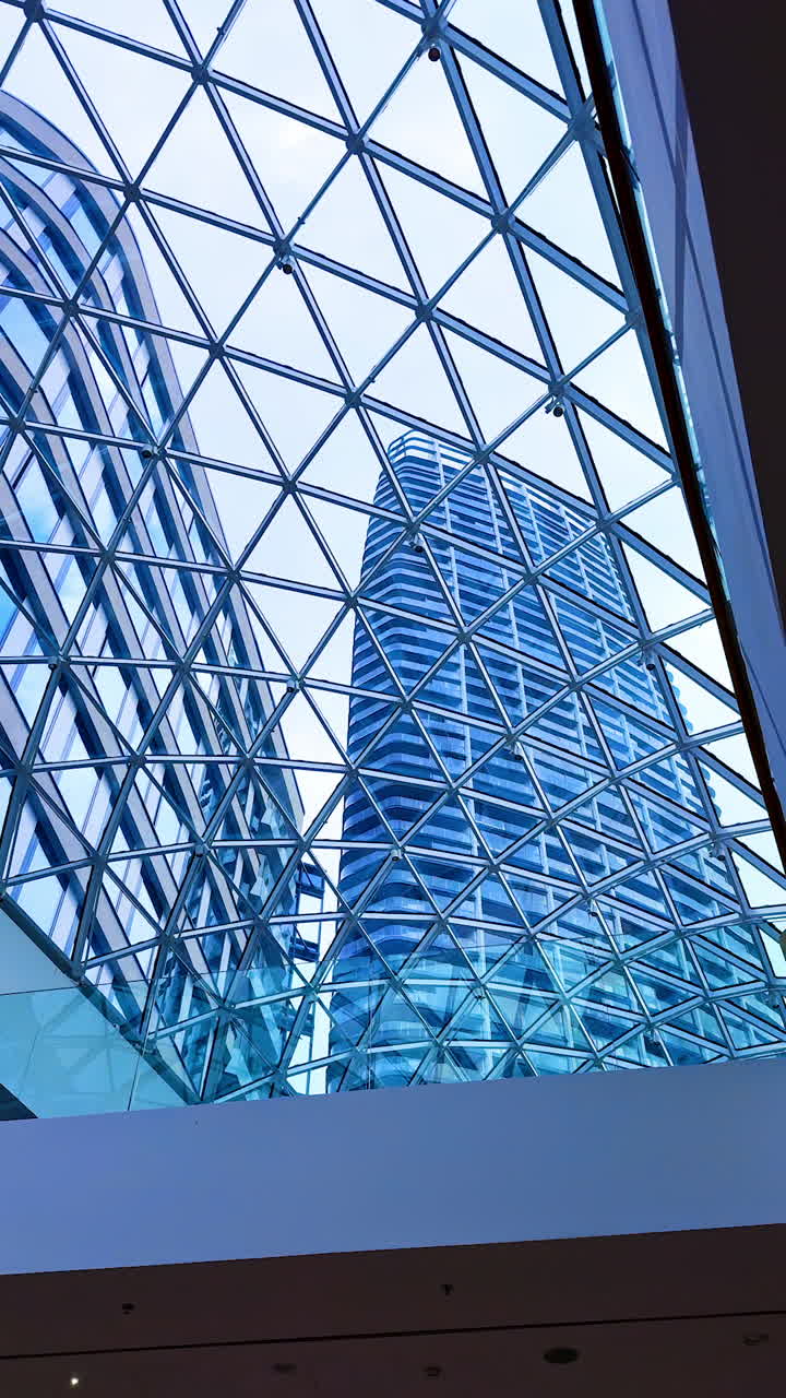 Modern architecture viewed from below. Looking up at a striking glass structure from the ground, showcasing geometric patterns and reflections in the windows
