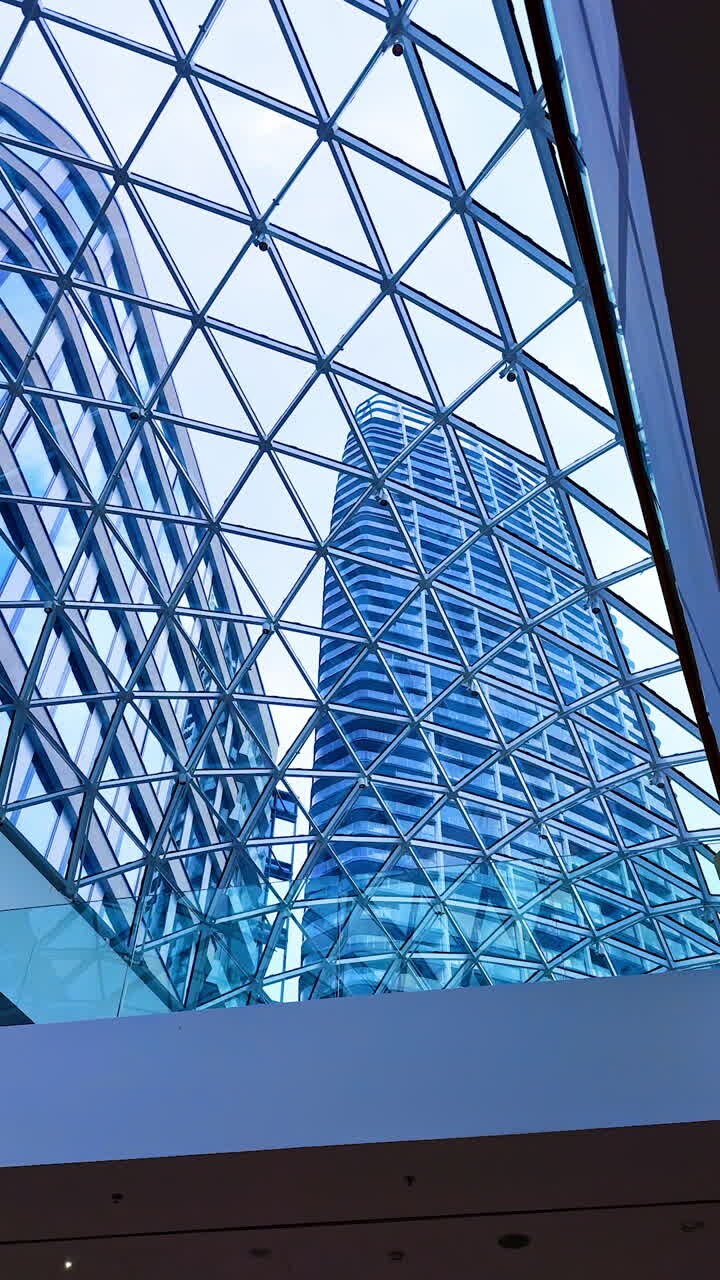 Arquitectura moderna vista desde abajo. Mirando hacia arriba una impresionante estructura de cristal desde el suelo, mostrando patrones geométricos y reflejos en las ventanas