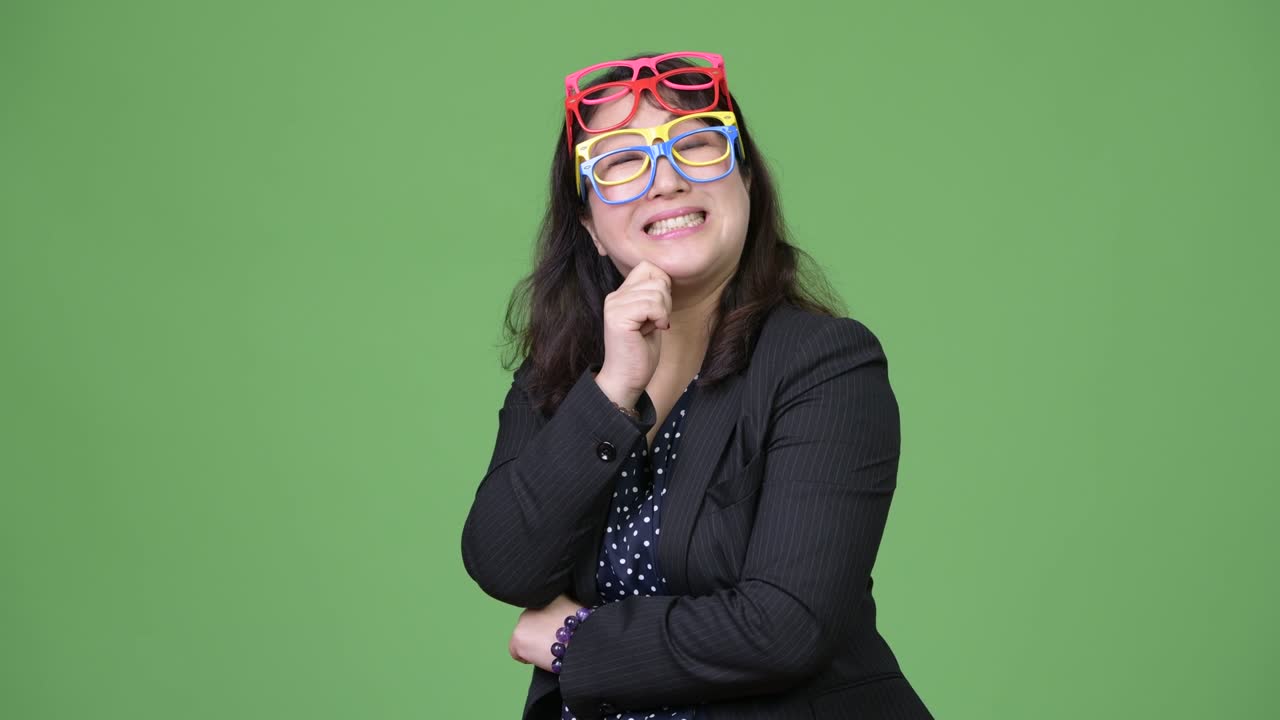 Mature beautiful Asian businesswoman wearing many eyeglasses as funny concept