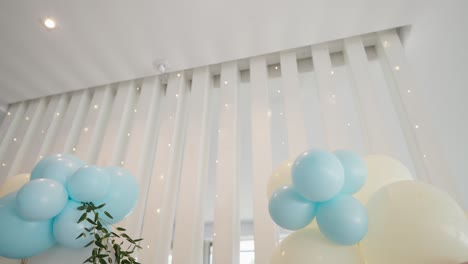 balloon decor in soft tones with leaves against white modern backdrop