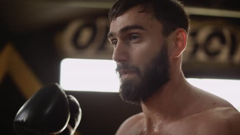 tired boxer wiping sweat from face at hard training. exhausted sportsman in gym