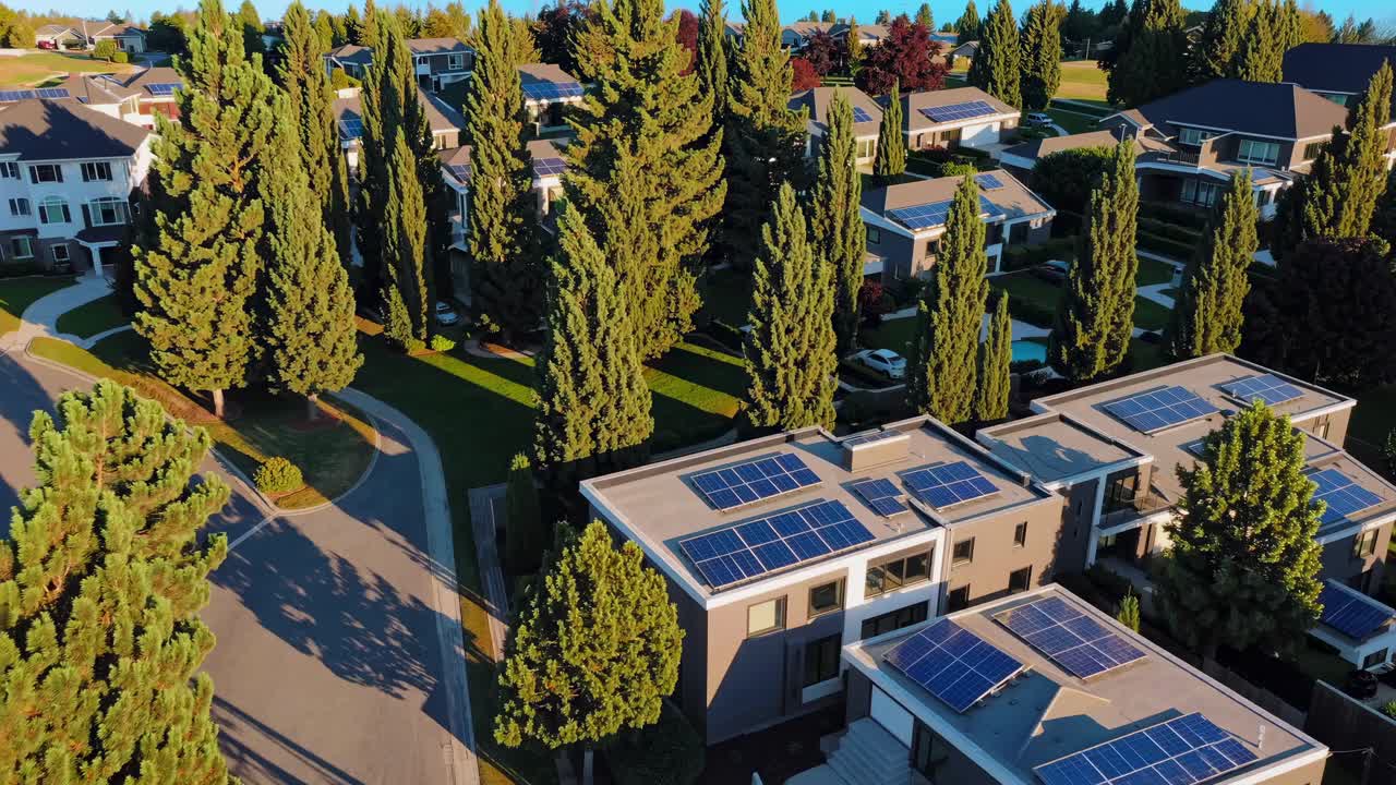 Aerial video view of modern homes with solar panels, surrounded by tall trees