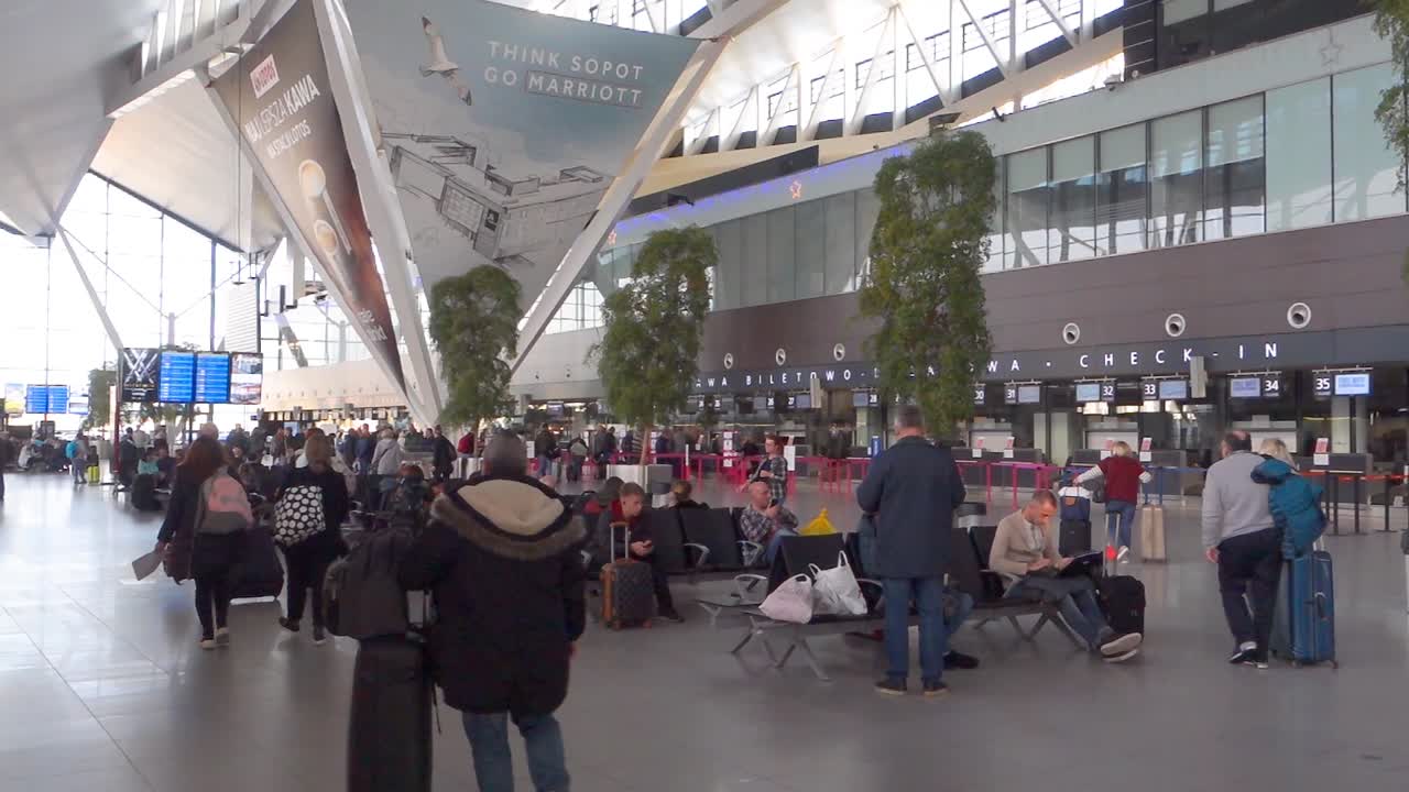 Interior of new modern terminal at Lech Walesa Airport in Gdansk. Arrival departure board at the terminal.People waiting in the terminal