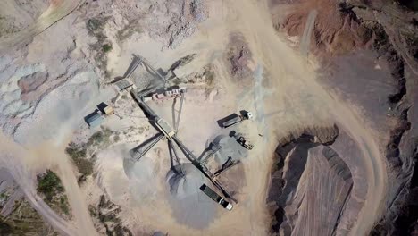 aerial-view-of-a-working-stone-quarry-with-stone-crushers,-bulldozers,-trucks-in-a-natural-environment-during-daytime