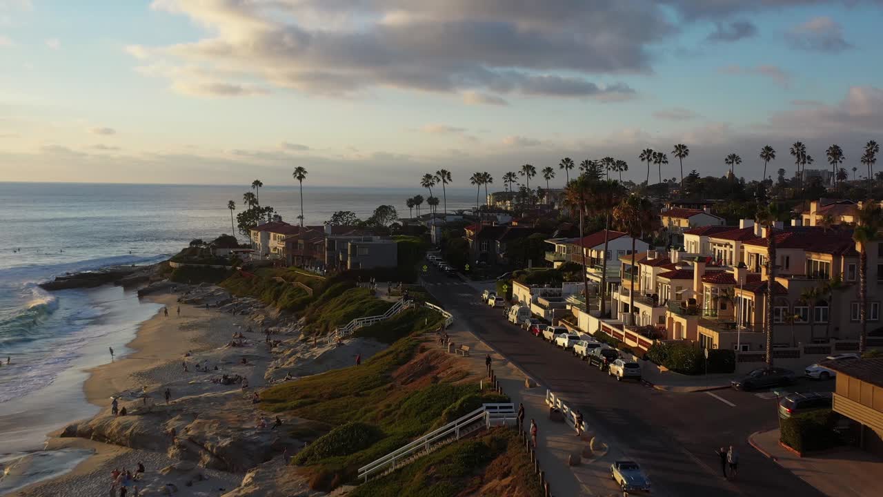 Drone che vola vicino alla spiaggia a La Jolla, San Diego, al tramonto, riprendendo surfisti e nuotatori che si godono l'oceano.