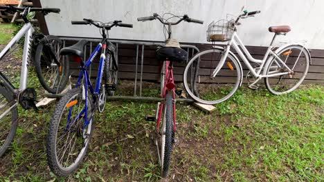 a series of bicycles leaning against a wall outdoors.