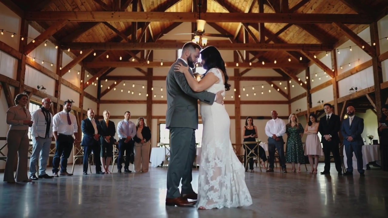 Musica che inizia, coppia di novelli sposi che ondeggia in una sala di fienile per il primo ballo, con abito da sposa e abito scuro.