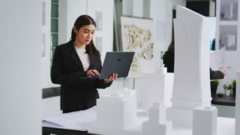 trabajador de una agencia inmobiliaria midiendo una maqueta de edificio impresa