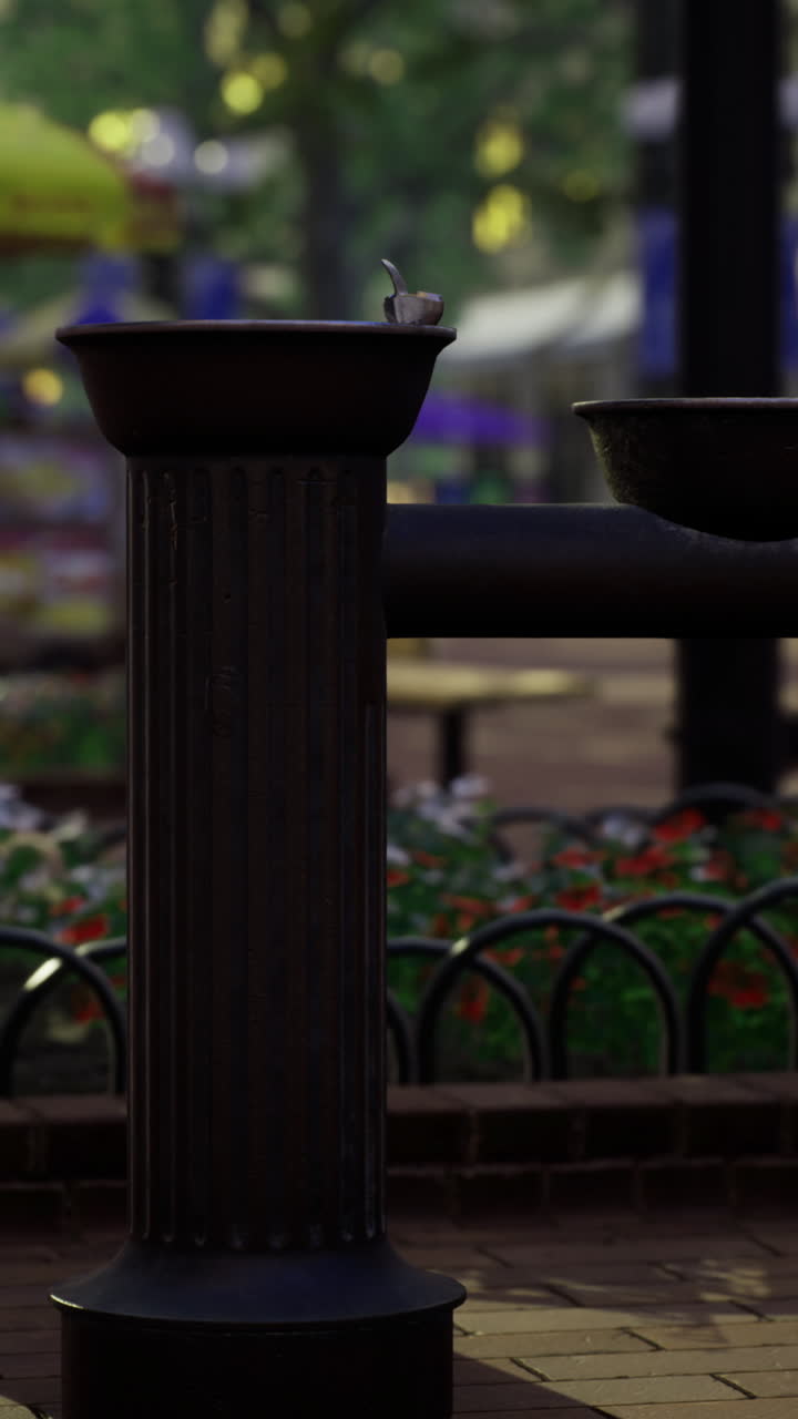 Public water fountain in a park surrounded by flowers and trees
