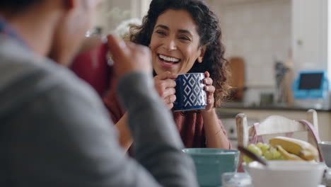 beautiful happy woman drinking coffee chatting to husband at home enjoying conversation in kitchen at breakfast