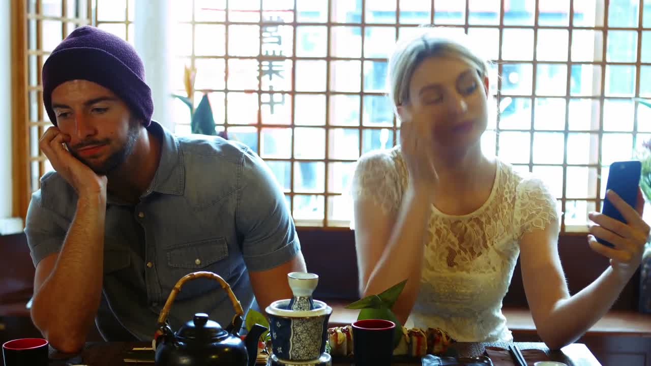 남자가 지루해지고 여자가  ⁇ 드폰으로 셀카를 찍습니다.