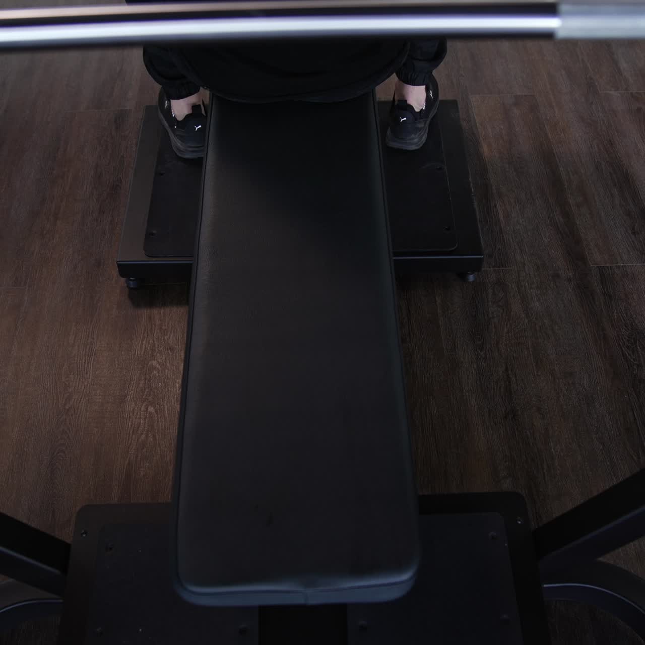 Handsome guy training on a modern sports equipment. Young athlete starts doing exercise on a simulator in gym. Muscular man exercising in fitness center. Top view