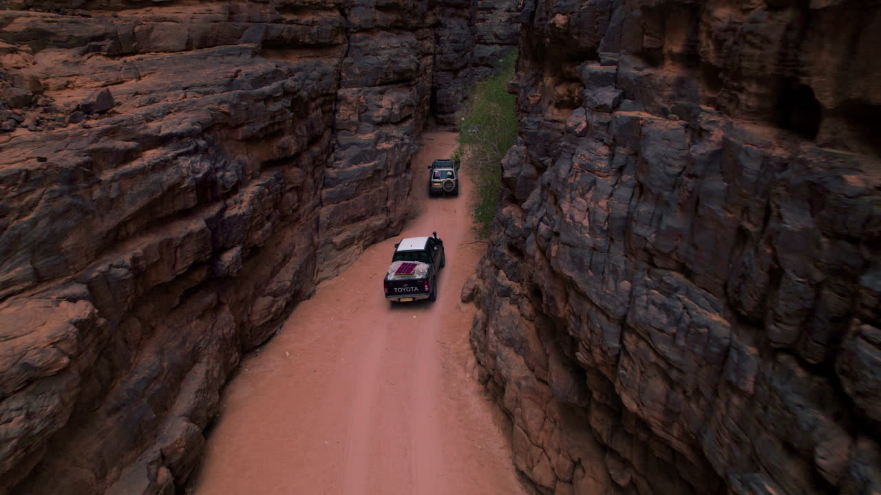 Offroad Vehicles Driving Through Rock Formations On Desert In Tassili N'Ajjer National Park, Illizi, Algeria