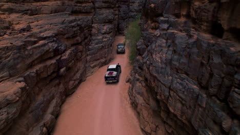 offroad vehicles driving through rock formations on desert in tassili n'ajjer national park, illizi, algeria