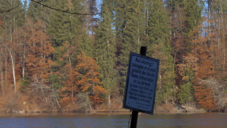 pan shot of a lake in late autumn, with a sign in the foreground, prohibiting boats and inflatables, at hackensee near holzkirchen