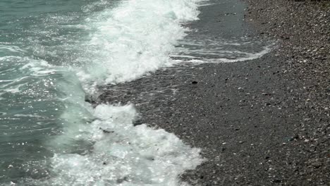 las olas golpean la orilla en la playa de kalamata, peloponeso, grecia, toma de revelación de inclinación en cámara lenta