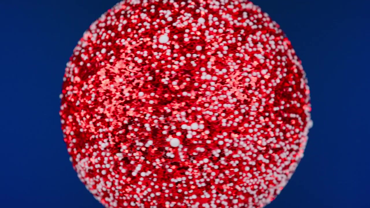 Red Glitter Christmas Ornament Shimmering on a Blue Background