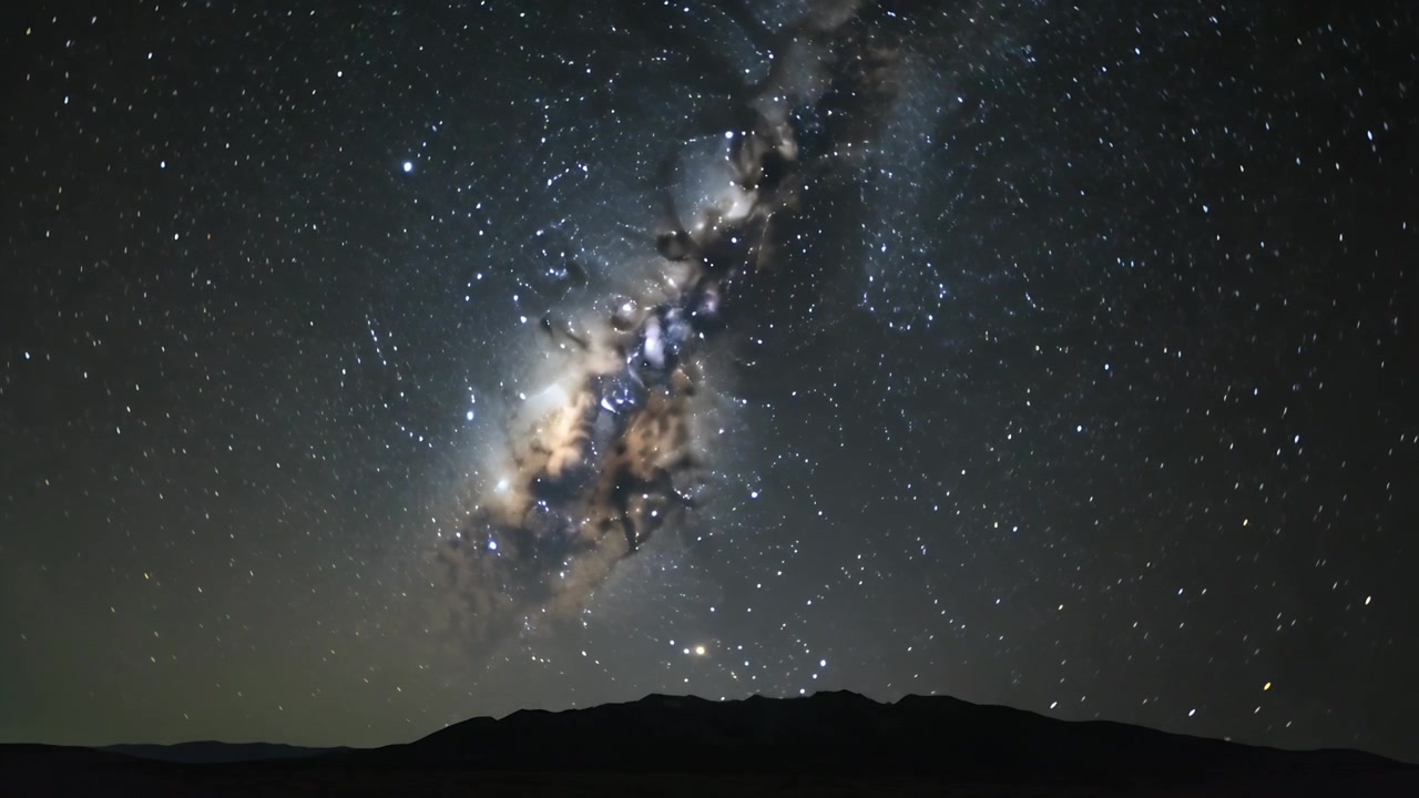 Timelapse som viser Melkeveiens kjerne, stjerner som vipper over mørk fjellrygg fra jordens rotasjon med horisontglød.