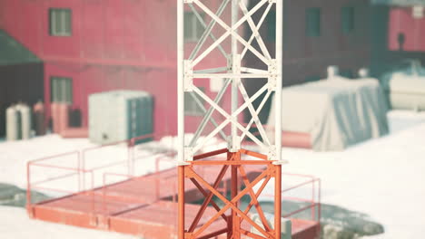una torre de metal roja y blanca se alza contra un telón de fondo nevado.