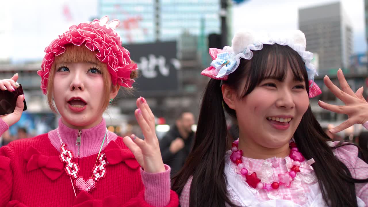 To unge kvinder iført farverige lyserøde Harajuku decora modeoutfits poserer og griner udendørs