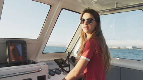 side view of a teenage caucasian girl driving a boat and looking at camera