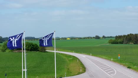 Ystad-flags-waving-in-the-wind,-aerial-view,-picturesque-green-landscape