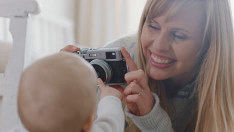 glückliche mutter, die mit der kamera ein foto von ihrem baby macht, aufgeregte mutter, die ein süßes kleinkind fotografiert, die den lebensstil der mutterlichkeit genießt, die erinnerungen macht