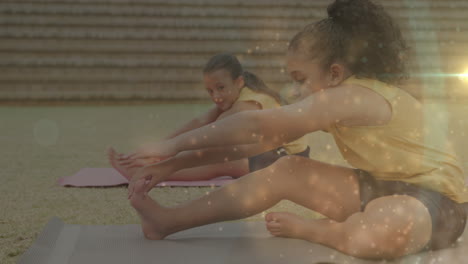 animation of bokeh lights over diverse schoolgirls exercising in outdoor yoga class