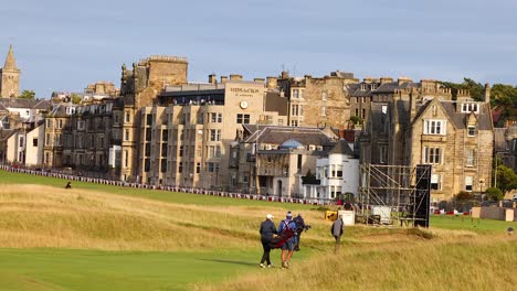 golfers walking on a field in st andrews