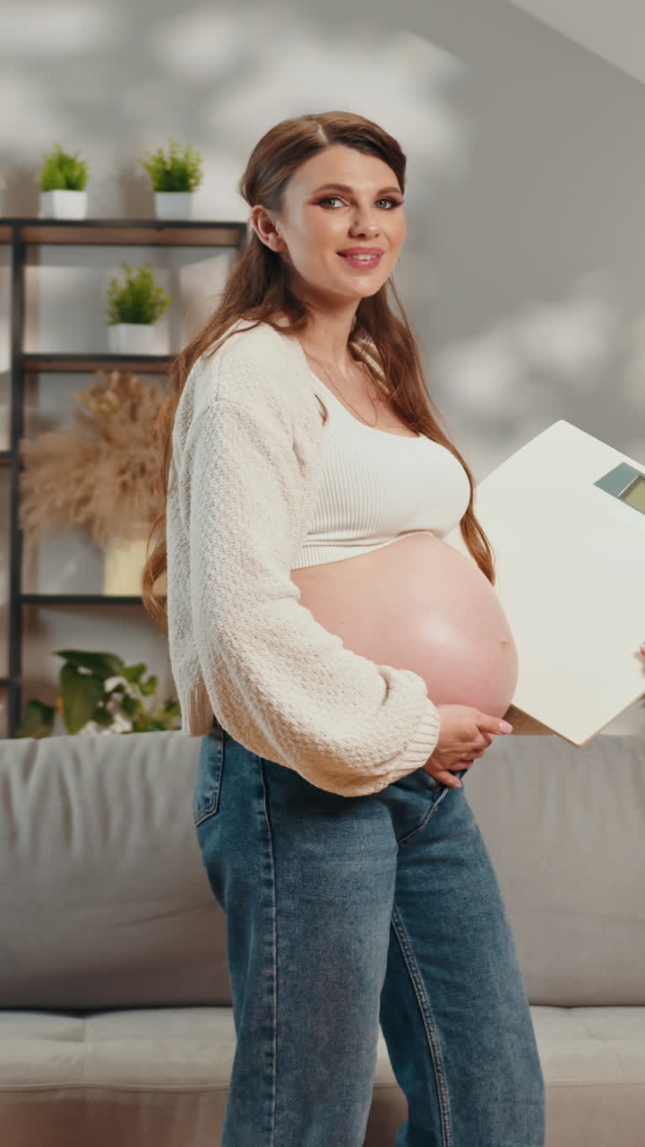 Pregnant woman holding scale monitoring weight gain during pregnancy feeling happy and content at
