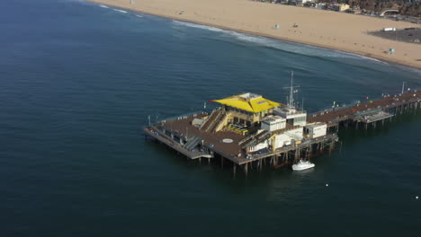 AERIAL:-Overlooking-Santa-Monica-Pier-in-Los-Angeles,-California,-Sunny,-Blue-Sky