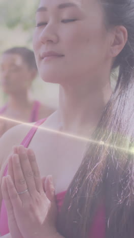 animation of light spots over diverse women practicing yoga and meditating