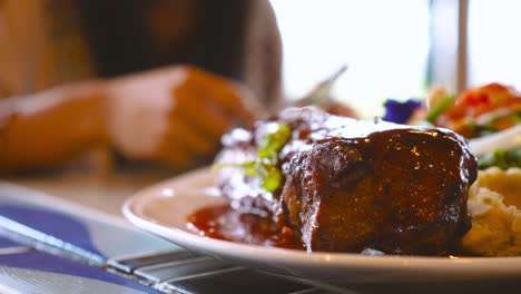 bistec de ternera recién cocinado en la mesa con una mujer asiática cenando en un fondo borroso. concepto de alimentación y dieta saludable.