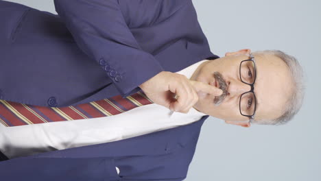 vídeo vertical de un viejo hombre de negocios diciendo cállate a la cámara.
