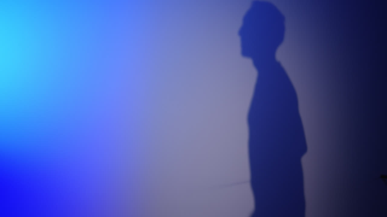 Shadow of Man Playing with Nunchaku on Blue Lit Wall