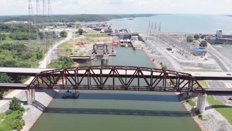 puente ferroviario y vehicular sobre el agua con barcazas atracadas en el puerto en el fondo, kentucky, retroceso aéreo