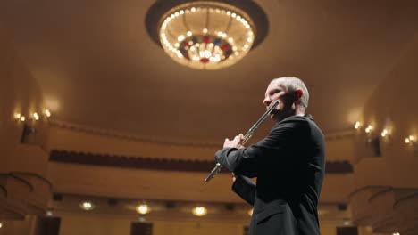 talented flutist is playing music in opera house or philharmonic hall portrait of musician with flute