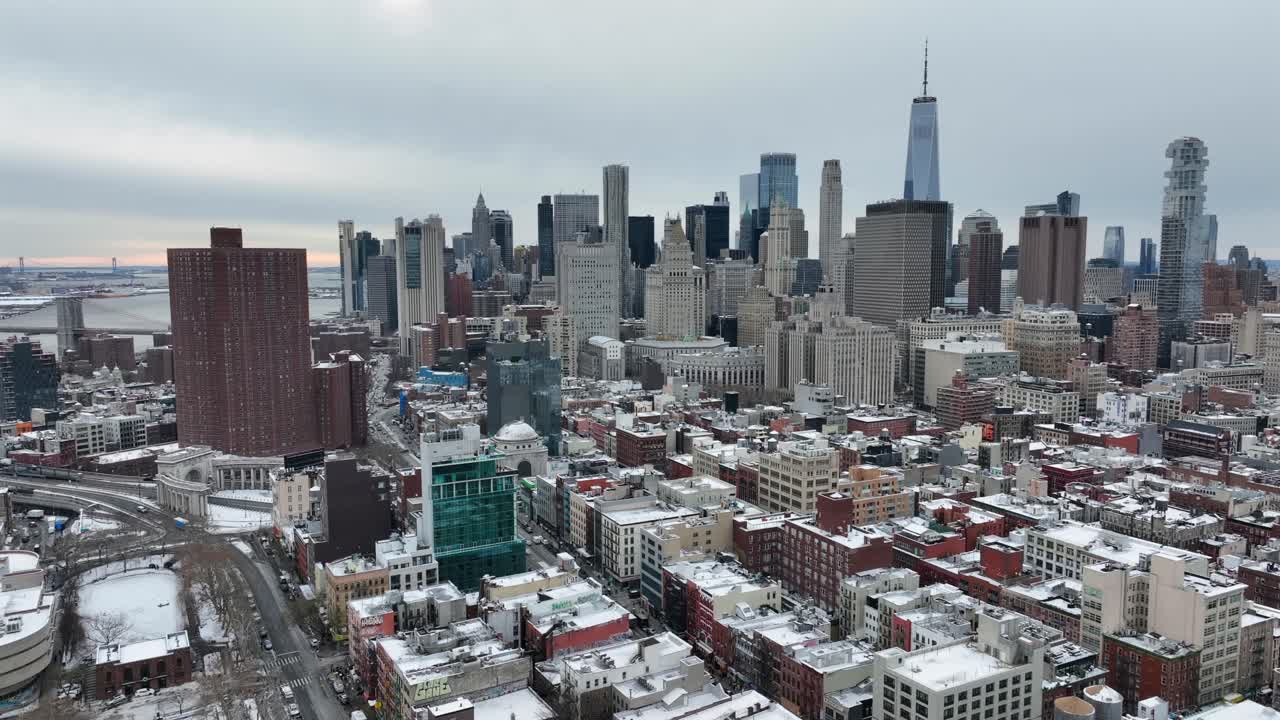 Snedækket New York City skyline med tætte bygninger og skyskrabere under en overskyet vinterhimmel. Etablerende luftfoto i bredt format
