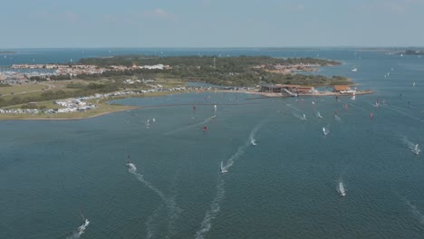 Drone---Aerial-shot-of-many-surfers-on-a-blue,-wavy-and-windy-sea-on-a-sunny-day-with-white-clouds-on-a-island,-25p