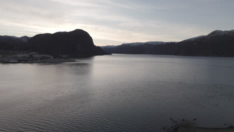drone shot flying over the water near forsand norway lysefjord during sunset on a clear day log
