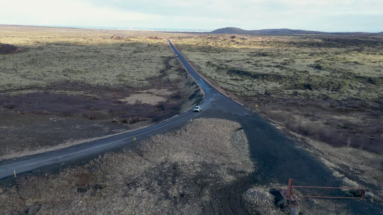 un vehículo en las tierras altas de islandia, paisajes de musgo, colinas, llanuras abiertas con un cielo azul profundo, nubes espumosas, océano brillante en la distancia