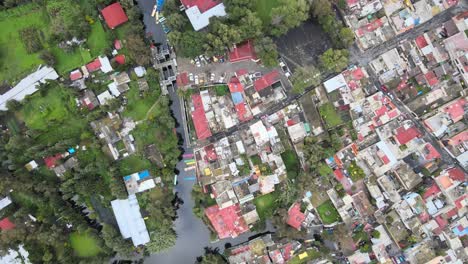 slowly jib down above houses, chinampas and canal in xochimilco, mexico city