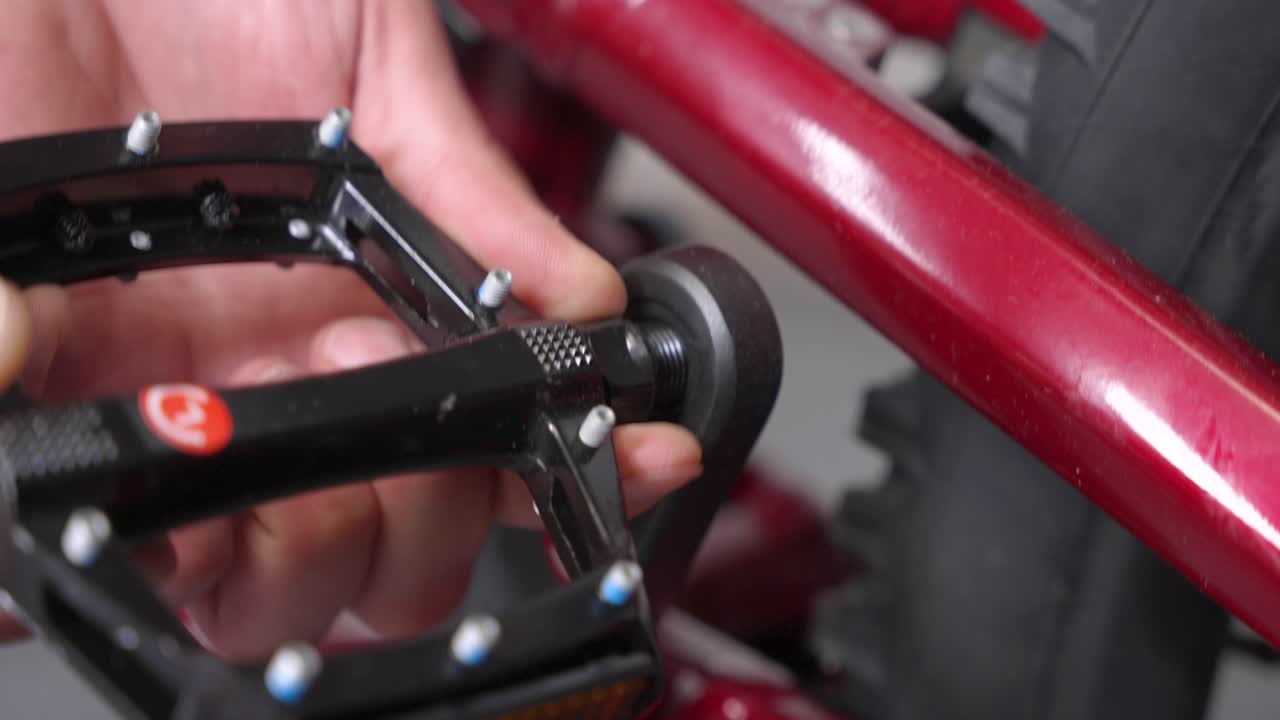 새로운 산악 자전거에서 손으로 느리게 왼쪽 페달을 크랭크 팔에 반시계 방향으로 스크류하는 자전거 기계