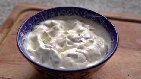 bowl of white dipping sauce with fried bacon and spring onions