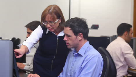 maestro ayudando a un estudiante maduro en la clase de computadora