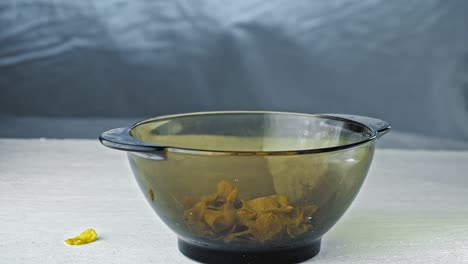 el hombre vierte en un plato de vidrio transparente vacío de copos de maíz por la mañana para el desayuno sólo queda para añadir leche